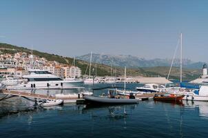 Inflatable motor boats stand next to yachts at the marina berths photo