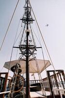 Captain at the helm of a wooden schooner sailing on the sea against the backdrop of an airplane flying in the sky photo