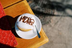 capuchino con un modelo en el espuma soportes en un taza en un platillo en el mesa. parte superior ver foto