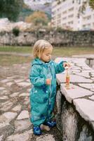 Little girl dipping a soap bubble stick into a bottle of liquid photo