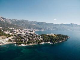Modern villas with terraces in the green gardens on the seafront. Dukley, Budva, Montenegro. Drone photo