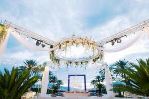 Round stand with spotlights decorated with flowers and white fabric above a laid festive table photo