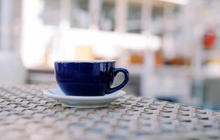 Latte in a cup on a saucer stands on a wicker table in an outdoor cafe photo