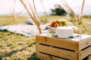 Boda pastel en un plato soportes en un de madera caja en un césped foto