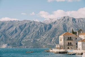 Excursion boat is moored to the coast with ancient stone houses. Perast, Montenegro photo