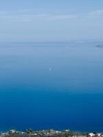 White sailboat sails on the blue sea against a clear horizon photo