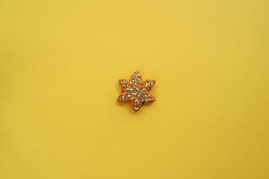 Glazed colorful gingerbread star lies on a yellow background photo