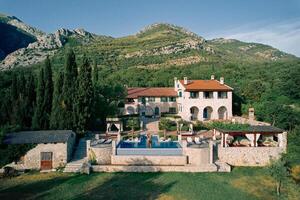 Man and woman hugging on the edge of a swimming pool near an old villa at the foot of the mountains photo