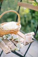 Wreath, a wicker basket with flowers and a box with jewelry stands on a wooden chair in the garden photo