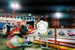 Little girl sits on an electric rocking horse swing at a fair and looks away photo