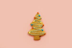 Christmas tree cookie with icing colorful garlands on a pink background photo