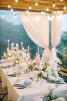 Set festive table with lit candles on a terrace with glowing garlands photo