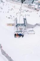 Skiers ride up the mountainside on a ski lift photo