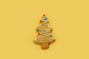 Navidad árbol Galleta con vistoso guirnaldas en un amarillo antecedentes foto