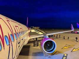 Milán, Italia - 12 noviembre 2023. pasajeros con equipaje caminar a lo largo el aeródromo a el avión escalera foto