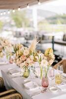 Bouquets of flowers in vases stand on the festive table among glasses and plates photo