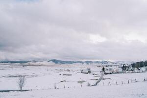 Small snowy village with pastures in a mountain valley photo