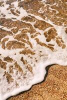 Sea foam rolls on the sunny sandy shore photo
