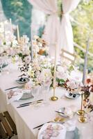 puesto festivo mesa con ramos de flores de flores y velas en candelabros soportes en el terraza foto