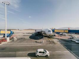 Afines, Greece - 20 august 2023. Plane with a telescopic gangway and airport services trucks stands on the runway photo