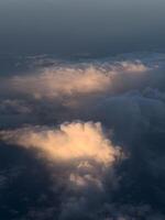 Porthole view of cumulus clouds in pink sunbeams on a dark blue background photo