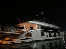 Budva, Montenegro - 25 december 2022. Illuminated white double-deck yacht stands at the pier at night photo