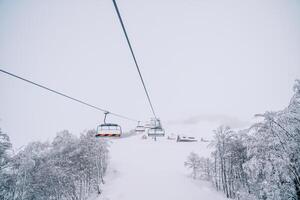 silla levantar sube arriba un Nevado montaña con pequeño casas foto