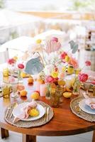 Plates with knotted napkins on mats stand on a festive table with colorful flowers photo