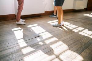 Men in sneakers stand on the wooden floor near the window. Cropped. Faceless photo