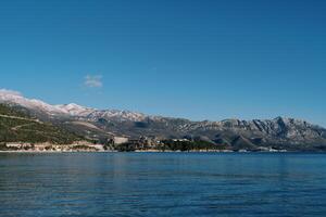 Mountain range with snow-capped peaks on the seashore photo