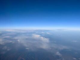 View from the porthole to the blue horizon and the earth under the clouds photo