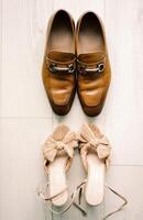 Bride and groom shoes stand opposite each other on a light laminate floor. Top view photo