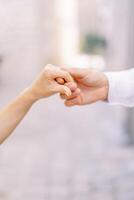 Groom holds bride hand in his own. Cropped. Faceless photo