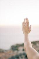 Woman examines an engagement ring at arm length. Cropped. Faceless photo