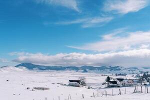 Snow-covered small village in a mountain valley in the sun rays photo