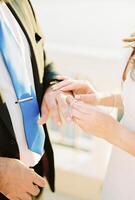 Bride puts the wedding ring on groom finger. Cropped. Faceless photo