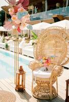 Bright wedding bouquet stands on a wicker armchair near the wedding arch photo