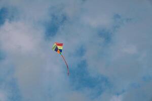 Colorful kite soars in the cloudy sky photo