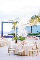 Laid festive table with a bouquet of flowers stands on a terrace with a glowing garland of light bulbs photo