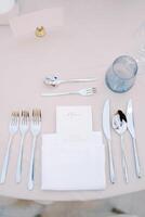 Personalized invitation lies in a white napkin on the table next to the cutlery, opposite a blank card on a stand photo