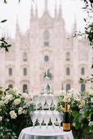 Stack of glasses on a table next to a bottle of champagne on a balcony overlooking the Duomo Cathedral. Milan, Italy photo