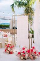 Seating plan hangs on a rectangular frame next to bouquets of flowers in front of the set festive tables photo