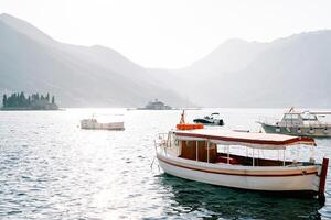 Moored excursion boats and motorboats at sea against the backdrop of the islands of the Bay of Kotor. Perast, Montenegro photo