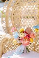 Colorful wedding bouquet of flowers stands on a wicker chair photo