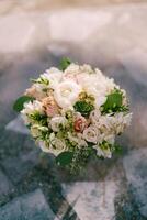 Pair of gold wedding rings lies on the bride bouquet standing on a tiled floor photo