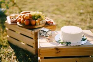 Boda pastel en un estar soportes en un de madera caja siguiente a un vaso caja foto