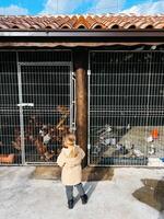 Little girl stands in front of a barn with chickens. Back view photo