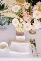 Name card stands next to a plate and a bouquet of flowers on a set table photo