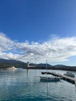 Boats moored at the pier against the backdrop of a lighthouse at the foot of the mountains photo