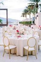 Chairs stand around a set festive table with bouquets of flowers photo